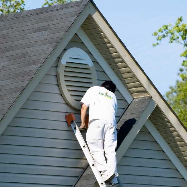 A The Honey Do Service craftsman painting the exterior of a beautiful house