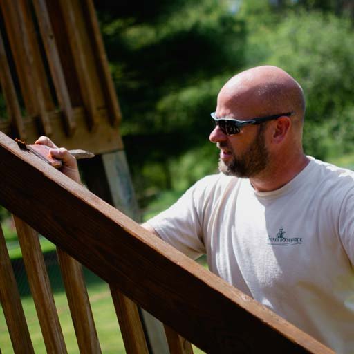 A Honey Do Service craftsman staining a wooden deck