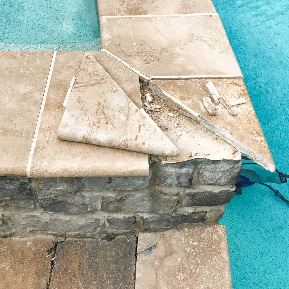 A broken marble tile from an outdoor swimming pool in desperate need for repair